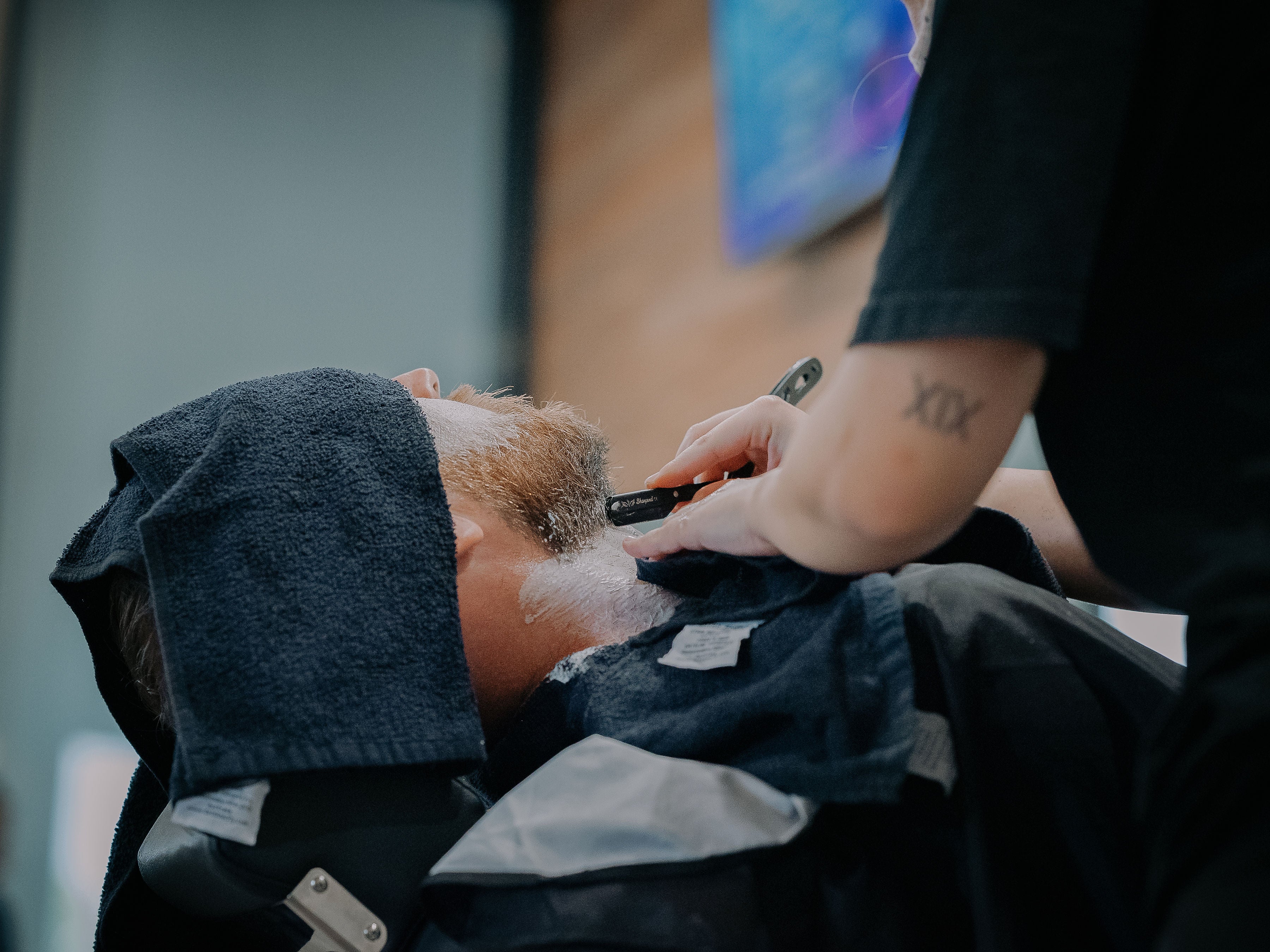 Person getting a cut-throat razor shave at HMB Barbers